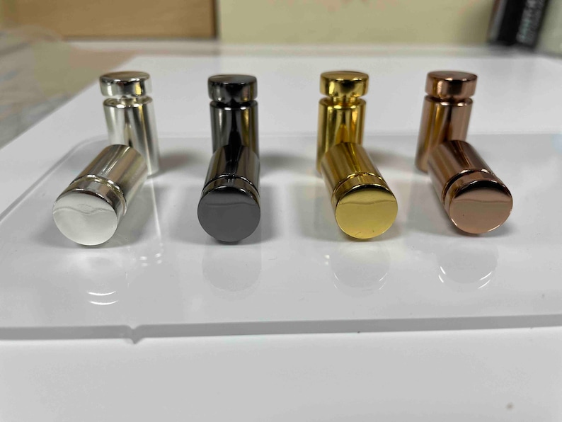 Pode incluir: Quatro suportes de exibi&ccedil;&atilde;o de metal em diferentes acabamentos: prata, preto, dourado e ouro rosa. Os suportes s&atilde;o cil&iacute;ndricos e t&ecirc;m uma parte superior arredondada.