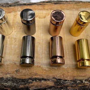 Pode incluir: Seis suportes de exibi&ccedil;&atilde;o de metal em diferentes acabamentos: prata, preto, cobre, ouro e mais dois acabamentos dourados. Os suportes s&atilde;o cil&iacute;ndricos e t&ecirc;m uma pequena borda na parte superior.