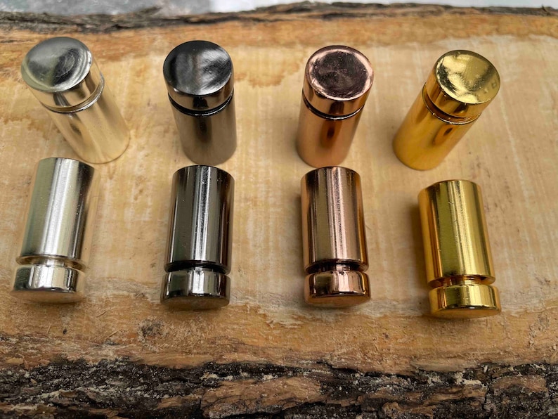Pode incluir: Seis suportes de exibi&ccedil;&atilde;o de metal em diferentes acabamentos: prata, preto, cobre, ouro e mais dois acabamentos dourados. Os suportes s&atilde;o cil&iacute;ndricos e t&ecirc;m uma pequena borda na parte superior.