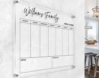 May include: A clear acrylic weekly planner with a black frame and the text "Williams Family" at the top. The planner has spaces for each day of the week, as well as sections for notes and a to-do list.