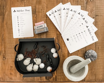May include: A black cauldron filled with toy eyeballs, spiders, and other Halloween-themed items.  A set of printable Halloween game cards with the title "Witches Brew" and a list of ingredients for a witch's brew.  A mortar and pestle and a small gray and black figurine of a pile of poop.