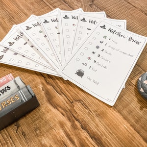 May include: A set of printable Halloween game cards with a witch's hat and the text "Witches' Brew". The cards have a checklist of ingredients for a witch's brew, including a frog, a scoop of magic dust, skulls, spiders, eyeballs, a rat, and instructions to mix well.