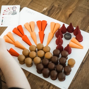 Könnte beinhalten: Eine weiße Tafel mit dem Wort "TURKEY" darauf. Die Tafel hat ein braunes, orangefarbenes und rotes Filz-Truthahn-Design. Das Design umfasst einen Körper aus braunen Kreisen, einen Kopf aus einem grauen Kreis und einen Schwanz aus orangefarbenen und roten Kegeln.