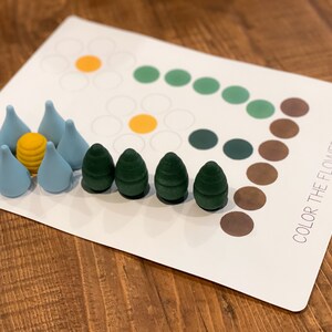 K&ouml;nnte beinhalten: Eine wei&szlig;e Karte mit dem Text "COLOR THE FLOWERS" darauf gedruckt. Die Karte hat ein Blumenmuster mit Kreisen in verschiedenen Farben. Es gibt kleine Holzst&uuml;cke in Blau, Gr&uuml;n und Gelb.
