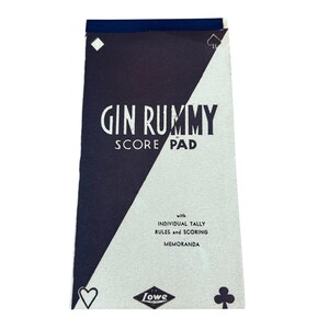 May include: A vintage Gin Rummy Score Pad with a navy blue and white design. The score pad features the text "GIN RUMMY SCORE PAD" in large white letters. The pad also includes the text "with INDIVIDUAL TALLY RULES and SCORING MEMORANDA".