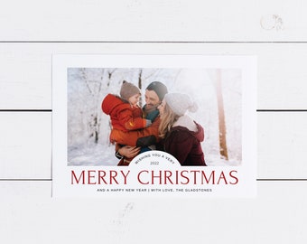 May include: A Christmas card featuring a family of three in a snowy winter scene. The card has the text "Wishing you a very 2022 Merry Christmas and a Happy New Year | With love, The Gladstones".