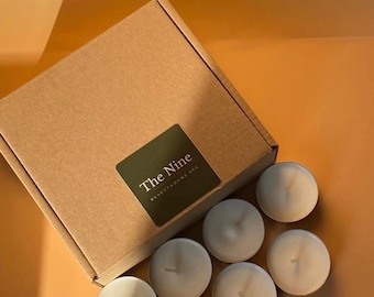 Może przedstawiać: Brązowe pudełko kartonowe z napisem "The Nine Beauty & Home Spa" z przodu. Pudełko jest otoczone dziewięcioma białymi świeczkami typu tealight.