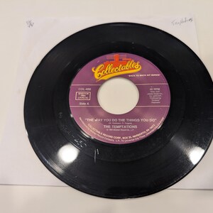 May include: A black vinyl record with a purple label. The label has the text "Collectables" and "The Way You Do The Things You Do" by "The Temptations".