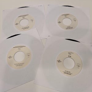 May include: Four 7-inch vinyl records by Jon Secada, each in a white paper sleeve. The labels feature the artist name, song titles including Angel and If You Go, and the text For Jukeboxes Only. The records are black with white center labels.