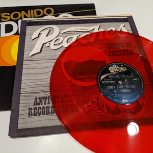 May include: A red vinyl record with a black label that says "Don't Stop 'Til You Get Enough" by Michael Jackson. The record is part of a limited edition collection and is in a clear plastic sleeve with a peach design.