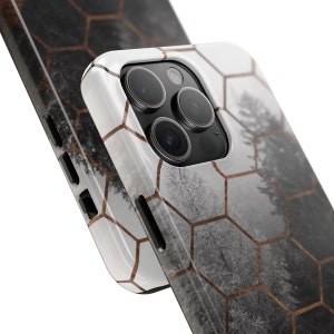 May include: A white phone case with a geometric honeycomb pattern and a blurry image of a forest in the background. The case has a raised camera bump with three black camera lenses.