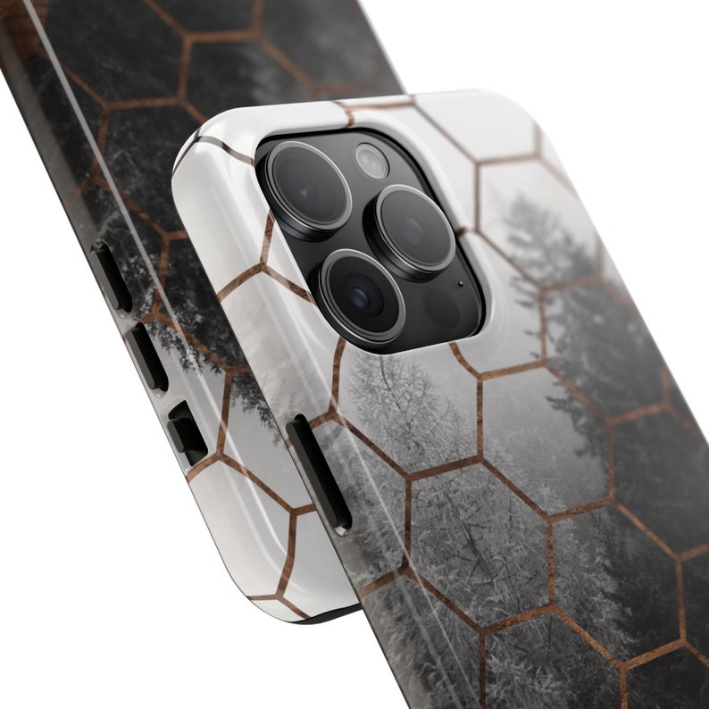 May include: A white phone case with a geometric honeycomb pattern and a blurry image of a forest in the background. The case has a raised camera bump with three black camera lenses.