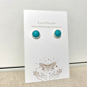 May include: Turquoise stud earrings with silver settings, presented on a white card. The card is printed with "katelifestyle Handcrafted Antique Accessories" and a butterfly and hand illustration.