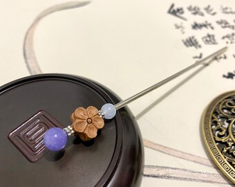 Puede incluir: Una varita para el pelo de plata con tres cuentas. Las cuentas son de color azul claro, una flor de madera marrón y otra cuenta de color azul claro.