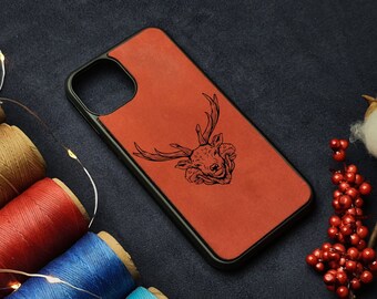 May include: A red leather phone case with a black deer head design. The case is surrounded by spools of colorful thread.