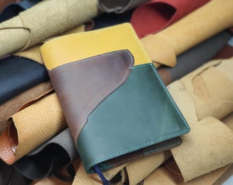 May include: A leather-bound journal with a green, brown, and yellow cover. The cover is made of different pieces of leather sewn together.
