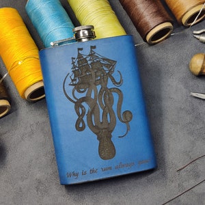 Puede incluir: Frasco de cuero azul con un diseño grabado de un pulpo sosteniendo un barco. El texto "Why is the rum always gone?" está grabado debajo del diseño.