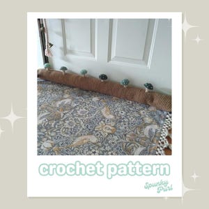 May include: A brown crocheted door draft stopper with small mushroom accents. The text "crochet pattern" is displayed at the bottom of the image. The stopper is placed in front of a white door and a patterned rug.