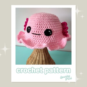 May include: A pink crochet hat with an axolotl face, featuring black eyes and a simple mouth. The hat has a ruffled brim and pink gills. The text "crochet pattern" is displayed at the bottom of the image.