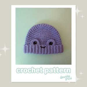 Puede incluir: Un gorro de crochet morado con una cara sonriente. El gorro tiene dos ojos negros y una boca negra. El gorro está sobre un fondo azul claro. crochet pattern Spunky Purl