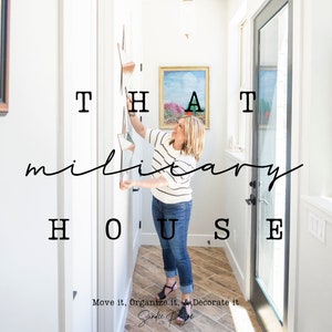 May include: A woman is hanging a star-shaped wall decor in a hallway. The text "THAT military HOUSE" is superimposed on the image. The text "Move it, Organize it, & Decorate it" is below the main text.