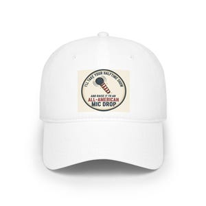 May include: White baseball cap with a curved peak. The cap has a circular patch with a microphone graphic and the text "I'll take your halftime show and raise it to an All-American Mic Drop."