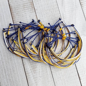 May include: A stack of blue, white, and yellow friendship bracelets with silver beads.