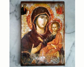 May include: A vintage, hand-painted icon depicting the Virgin Mary holding the baby Jesus. The icon is painted on a wooden panel and has a distressed, aged look. The colors are muted and earthy, with shades of brown, red, and gold.