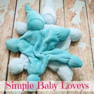 May include: Two soft, plush baby loveys in blue and light blue. The loveys are shaped like a star with a small head on top. The loveys are made of a soft, cuddly fabric and are perfect for babies to cuddle with.