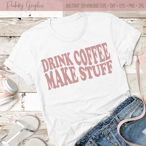 Puede incluir: Camiseta blanca con el texto "Drink Coffee Make Stuff" en fuente retro rosa.