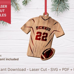 Puede incluir: Un adorno de madera con forma de camiseta de fútbol con el nombre "DENNIS" y el número "22" en la parte delantera. Se incluye un balón de fútbol debajo de la camiseta. El adorno está listo para ser personalizado con un nombre y un número.