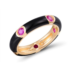 May include: A black enamel ring with a gold band and four pink gemstones.