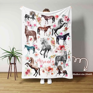 May include: White fleece blanket with a floral design and multiple watercolor images of horses. The blanket has the name "Miranda" printed in pink lettering.