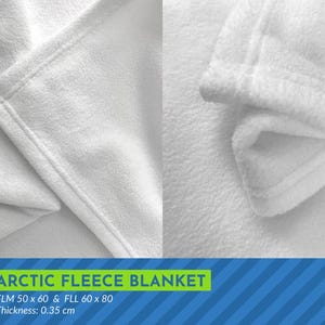 May include: Close-up of a white fleece blanket folded in half. The blanket is soft and fluffy, with a smooth texture. The text "ARCTIC FLEECE BLANKET" is printed in green on a blue and white striped background. The text "FLM 50 x 60 & FLL 60 x 80" and "Thickness: 0.35 cm" is also printed on the background.