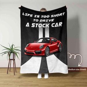 Könnte beinhalten: Eine schwarze und weiße Fleece-Decke mit dem Text "Life is too short to drive a stock car" und einem roten Sportwagen auf einer weißen Straße. Die Decke ist mittelgroß (50x60 Zoll).
