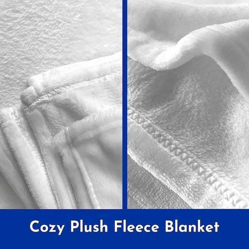 Op de afbeelding: Close-up van een wit, pluche fleece deken. Het deken is gevouwen en laat de zachte textuur van de stof zien. Het deken wordt beschreven als "Gezellig Pluche Fleece Deken".