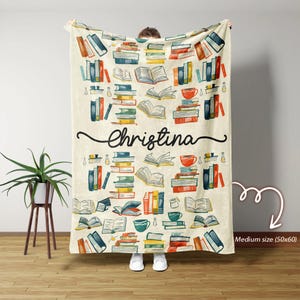 Può includere: Una coperta in pile color crema con un motivo colorato di pile di libri, tazze da caffè e il nome "Christina" stampato in nero. La coperta misura 50 pollici per 60 pollici.