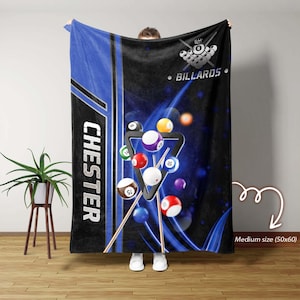 May include: A medium-sized, black and blue pool-themed blanket. The blanket features a graphic of billiard balls, a triangle rack, and the word "BILLIARDS". The name "CHESTER" is printed vertically in white on a blue stripe.