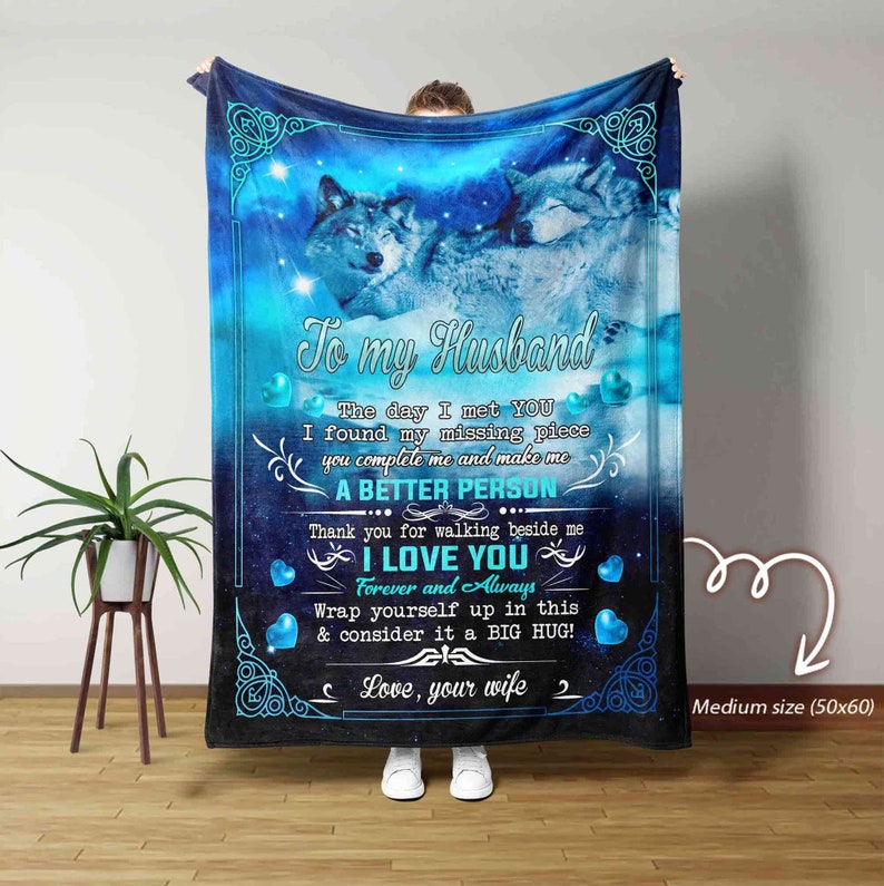May include: A blue and black fleece blanket with a couple of wolves cuddling on a starry sky background. The blanket has the text "To my Husband" and "I love you" with hearts and a message about finding a missing piece. The blanket is 50 inches by 60 inches.