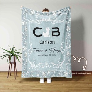 Peut inclure: Une couverture en polaire bleu clair avec un motif floral blanc. La couverture présente un monogramme avec les initiales "CB" et le nom "Carlson". Le texte "Forever & Always" et "Married Sept. 20, 2024" est également inclus. La couverture mesure 127 cm sur 152 cm.