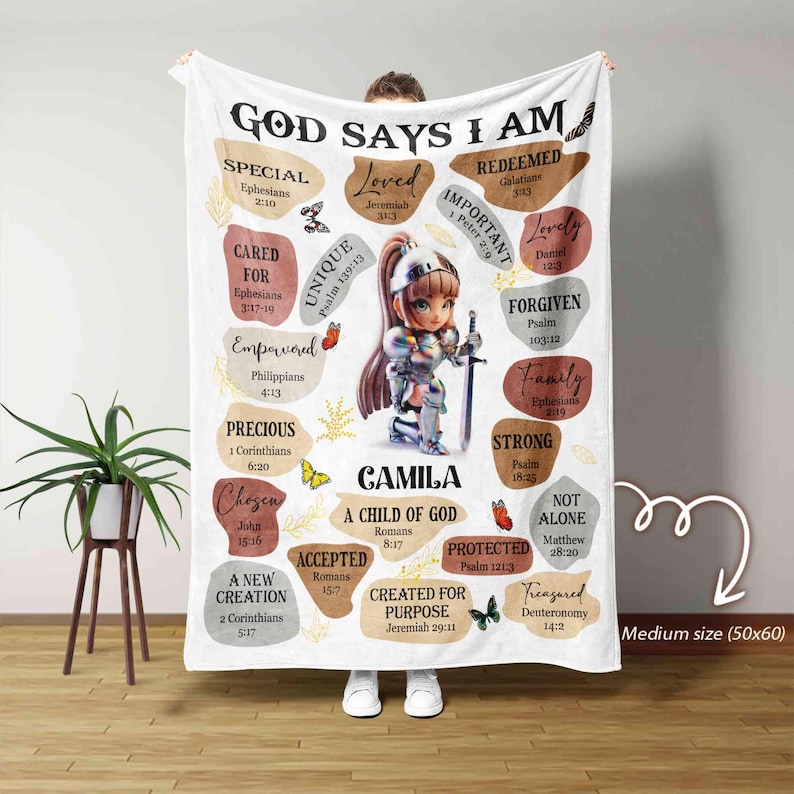 May include: White fleece blanket with a colorful design featuring a girl in armor and the words "God Says I Am" with bible verses and inspirational phrases. The blanket is personalized with the name "Camila" and the phrase "A Child of God".