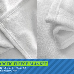 May include: Close-up of a white fleece blanket with a soft, fuzzy texture. The blanket is folded over, showing the stitching along the edge. The text "ARCTIC FLEECE BLANKET" is printed in green letters on a blue and white striped background. The text "FLM 50 x 60 & FLL 60 x 80" and "Thickness: 0.35 cm" is also printed below the blanket.