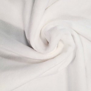 May include: White fabric with a soft, smooth texture. The fabric is folded and draped, showing its smooth surface and subtle wrinkles.
