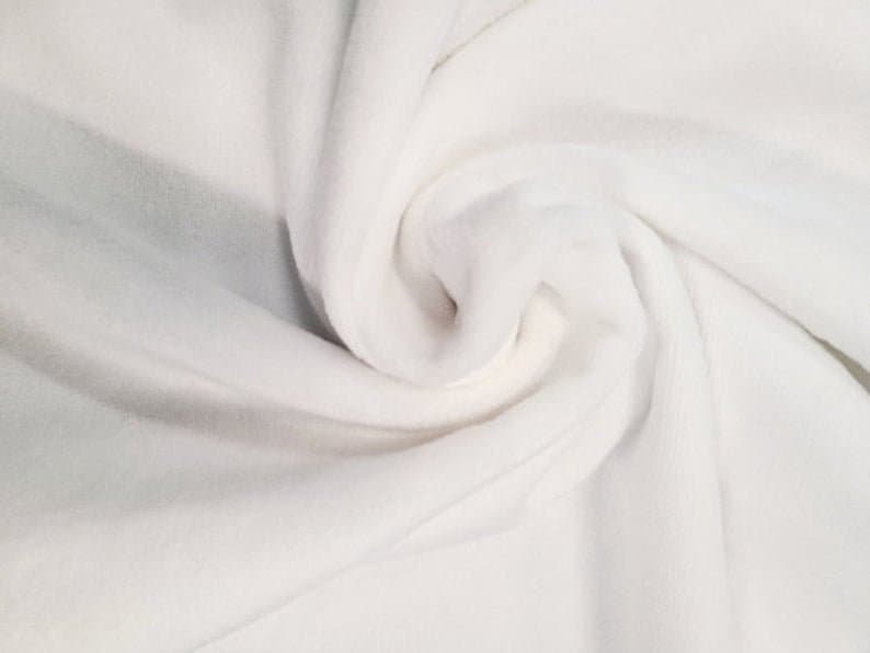 May include: White fabric with a soft, smooth texture. The fabric is folded and draped, showing its smooth surface and subtle wrinkles.