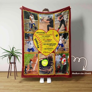 May include: A maroon fleece blanket featuring a collage of photos of a young girl playing softball. The blanket includes a heart-shaped softball with the girl's name "EMILIA" and a list of positive attributes, such as "I am strong, I am bold, I am a fighter, I am smart, I am relentless, I am brave, I am tough, I am powerful, I am a pitcher".