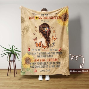 May include: A tan blanket with a sunflower and butterfly design. Text reads "TO MY BADASS DAUGHTER Trisha" and a quote. The blanket is medium size, 50x60 inches.