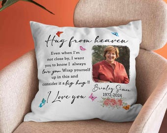 Puede incluir: Una almohada blanca con un mensaje que dice "Hug from heaven. Even when I'm not close by. I want you to know I always love you. Wrap yourself up in this and consider it a big hug!! I love you."  La almohada también presenta una foto de una mujer, mariposas y el texto "Brinley Simon 1972-2024".