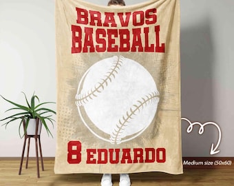 May include: A tan and beige fleece blanket with a baseball graphic and the text "Bravos Baseball 8 Eduardo" in red. The blanket is medium size (50x60 inches).