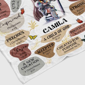 May include: A white blanket with a colorful design featuring a knight kneeling with a sword. The design includes the name "CAMILA" and various bible verses, including "A Child of God", "Strong", "Precious", "Chosen", "Accepted", "A New Creation", "Protected", and "Created for Purpose".