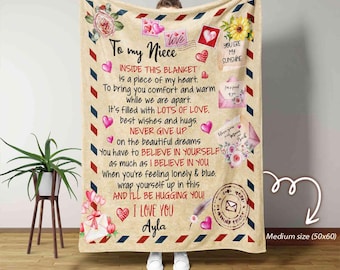 May include: A beige blanket with a printed message to a niece, featuring floral and heart designs. The text includes phrases like "To my Niece," "I Love You," and "Never Give Up." The blanket is a medium size, 127x152 cm.